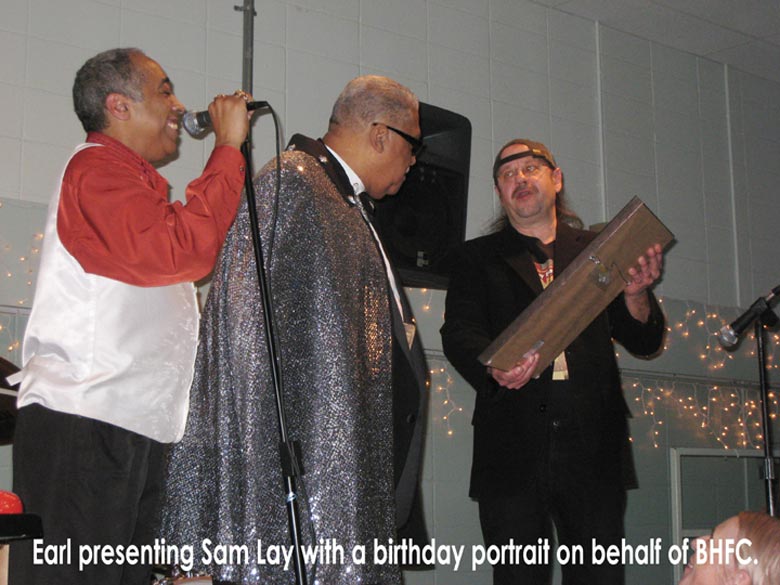 Earl presenting a birthday portrait to Sam Lay
